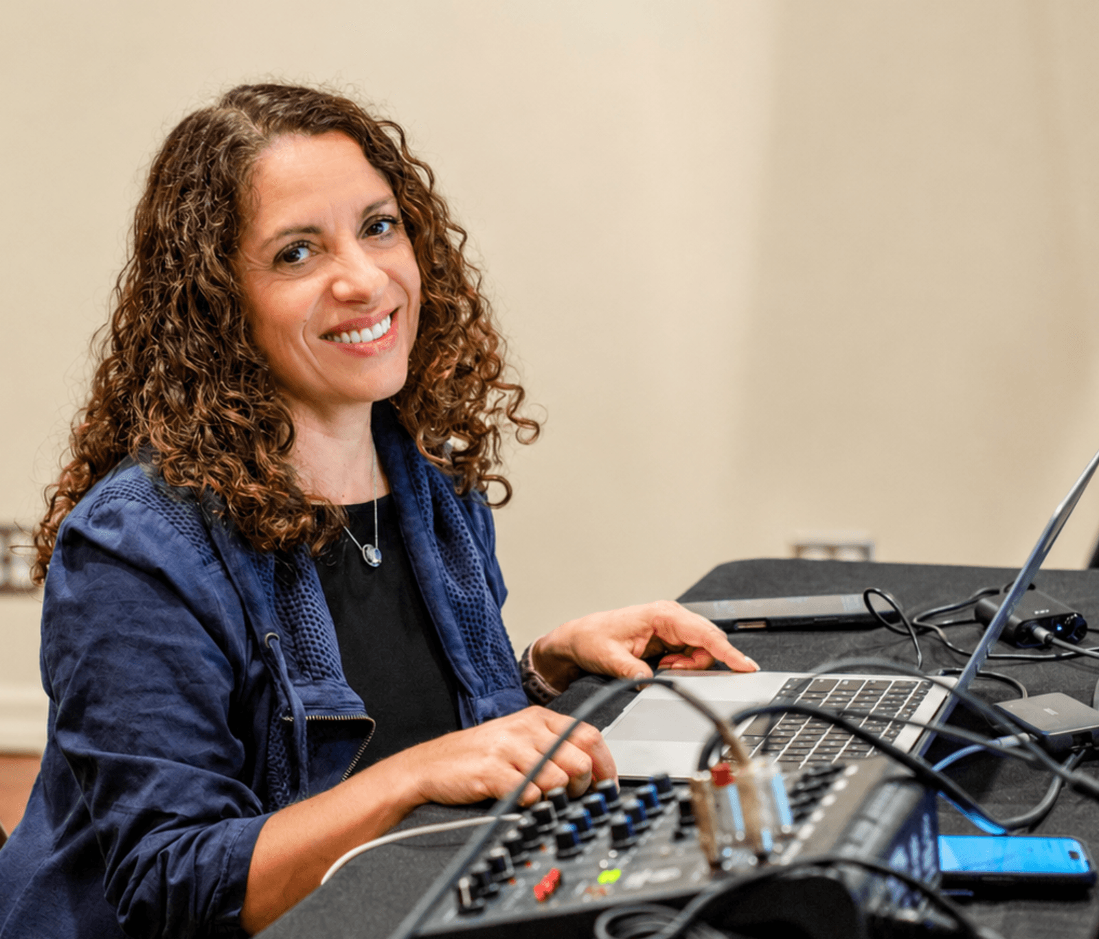 DJ Ella at the decks — warm studio light, focused and in her element